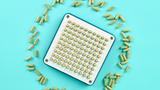 Blated 100-hole capsule filling machine tray loaded with size 00 green capsules ready to fill