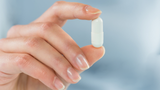 Close-Up Of A Hand Holding A White Enteric Coated Capsule