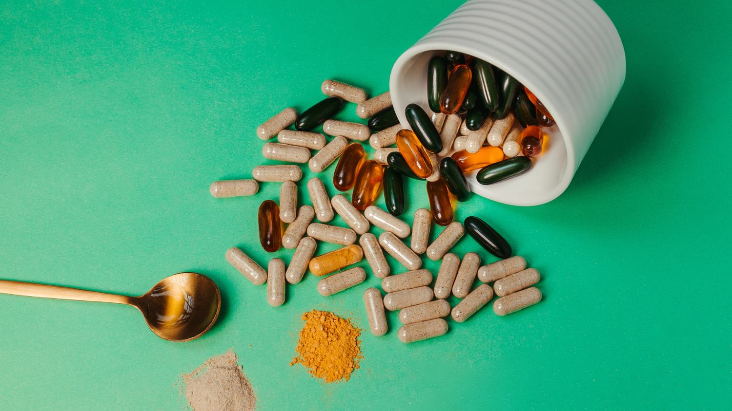 Gelatin and vegetarian capsules spilled from container on surface