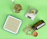 Herbal products including a jar, scale, and container on a green background